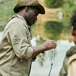 African American dad fishing together with his son near the lake